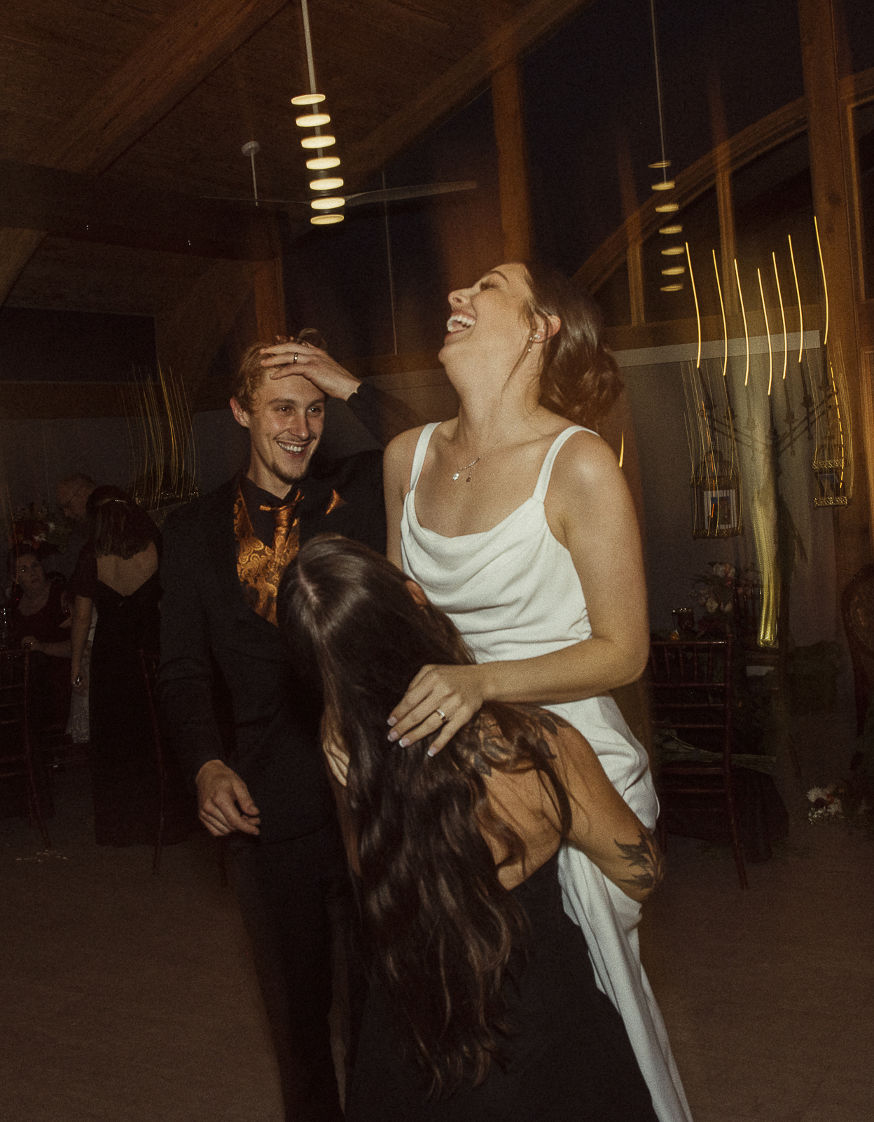 Candid wedding reception photo of a bride laughing with friends on the dance floor, captured in warm flash lighting- editorial-style wedding photography in St. Augustine.