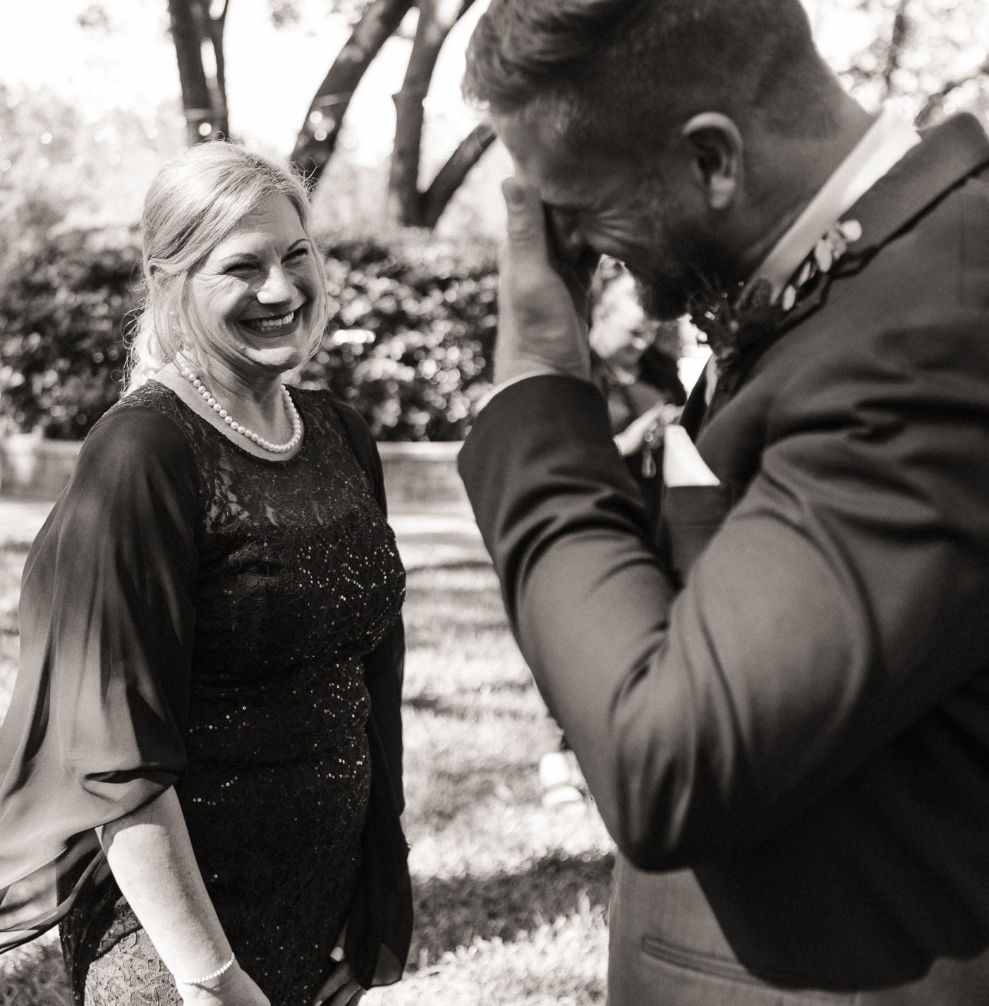 Groom and mother sharing a laugh after ceremony in Jacksonville, Florida, documentary style. 